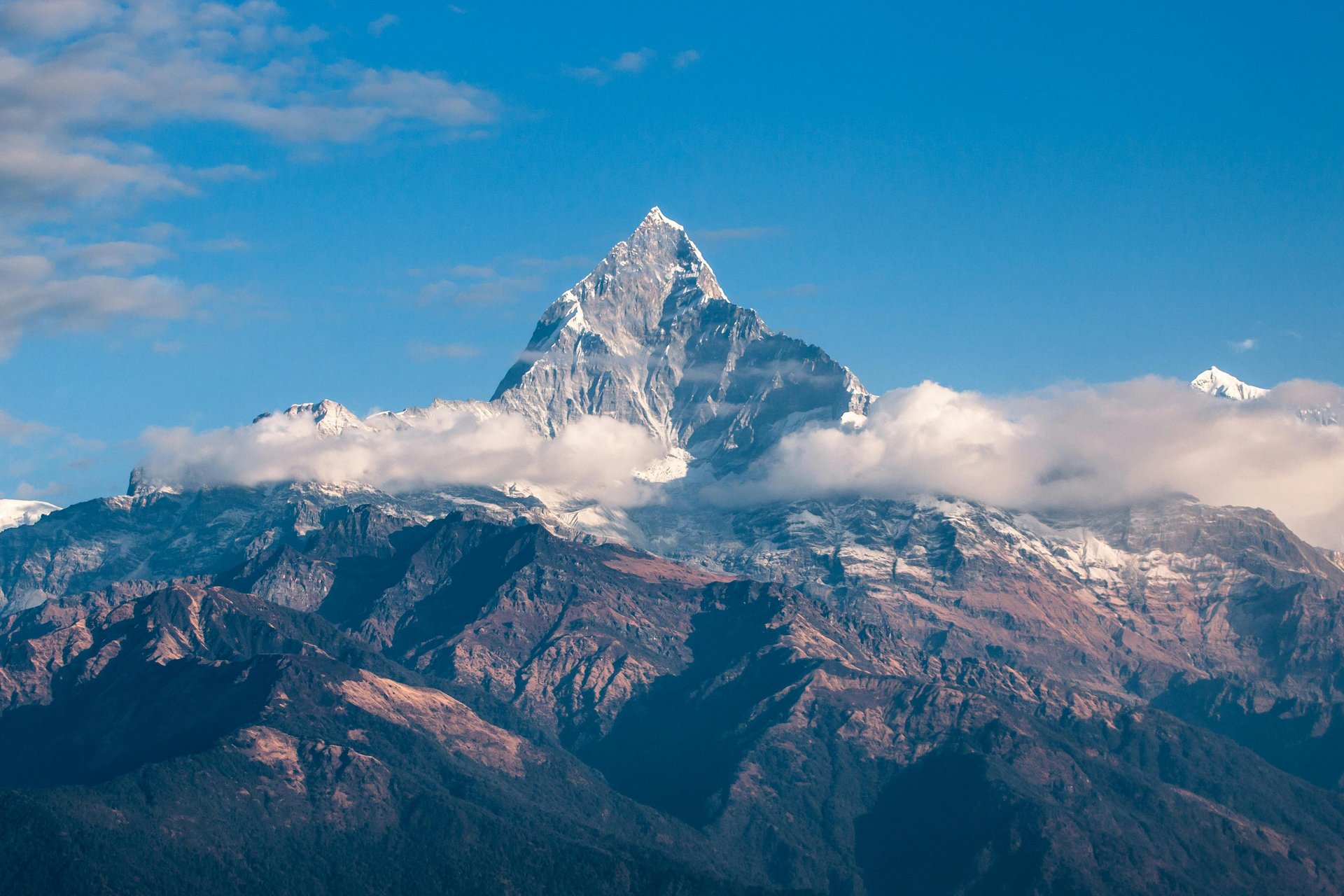 A snow-capped mountain peak rising above a valley at dawn